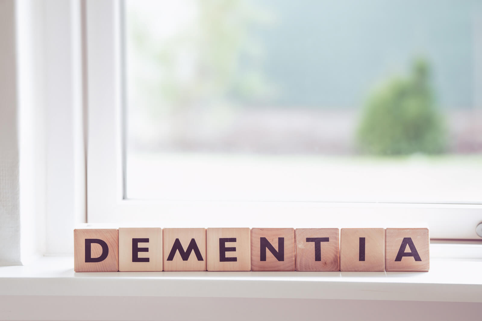 Wooden blocks with letters spelling dementia on a window sill.