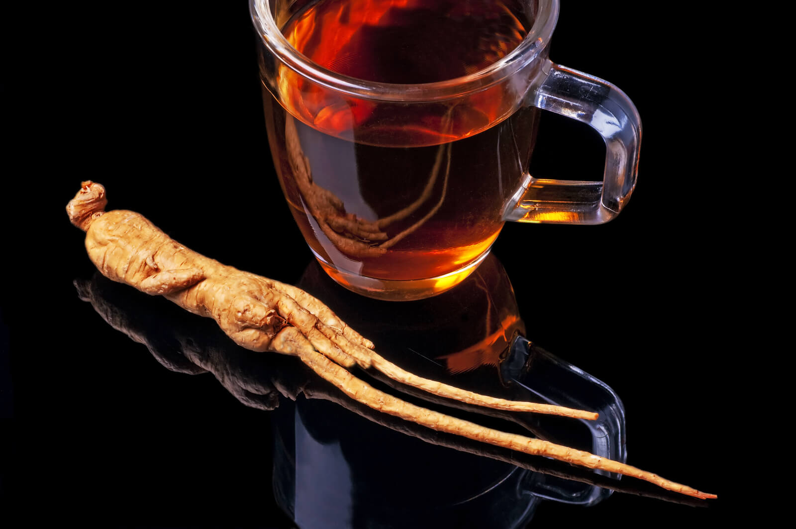 A cup of ginseng tea with a ginseng root.