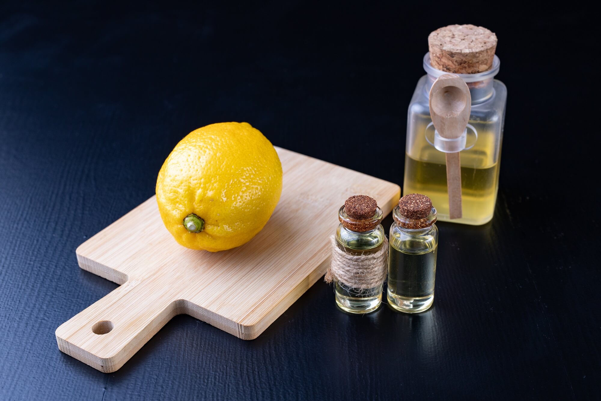 Lemon fruit on wooden board with herbal extracts or essential oil bottles.