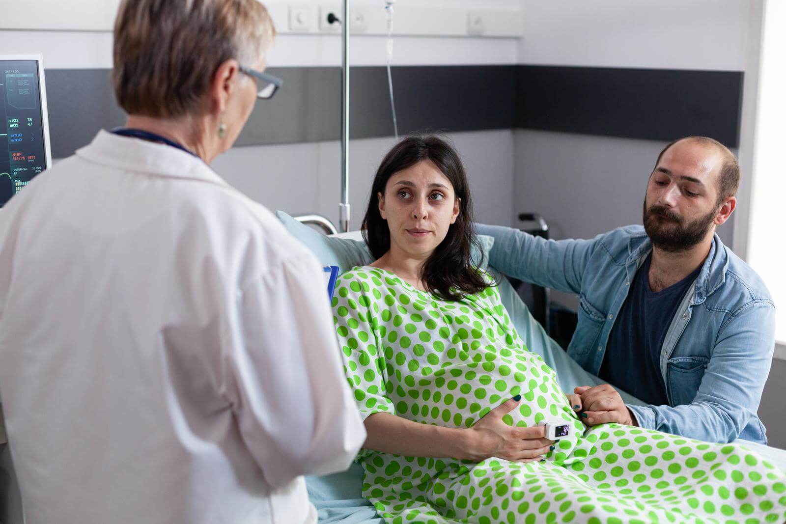 Female obstetrics doctor talking to couple with pregnancy.