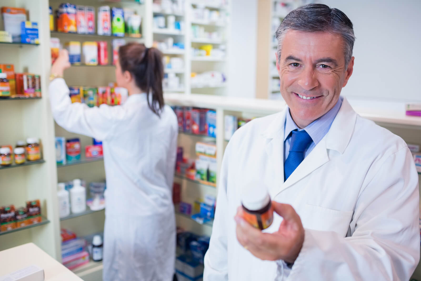 Smiling pharmacist holding a bottle of pills