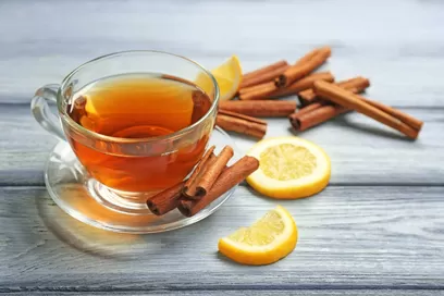 Cinnamon tea in glass cup with slices of lemon.