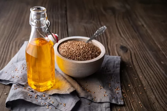Flaxseed oil in a glass bottle, decorated with whole seeds with copy space — Photo