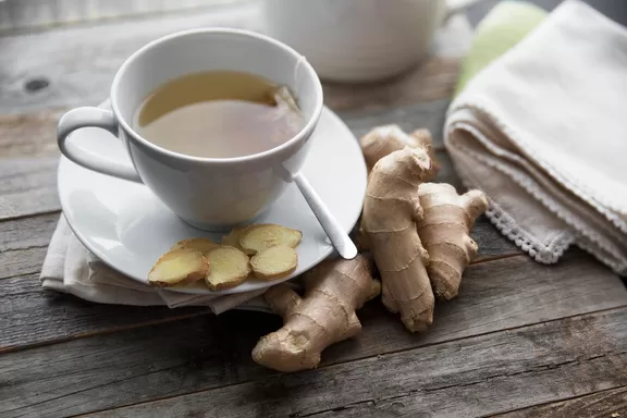 Ginger tea with ginger roots and slices on table.
