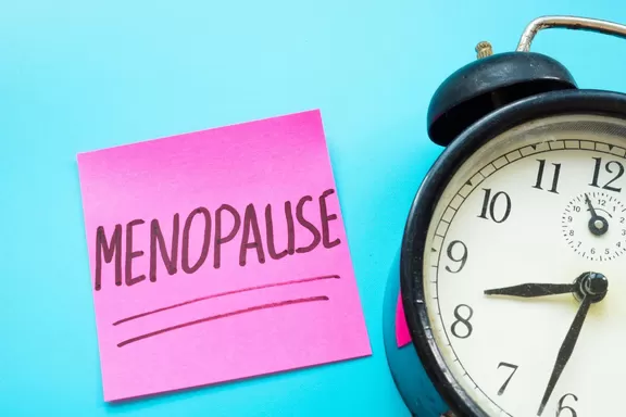 Menopause word handwritten on the sticker and alarm clock.