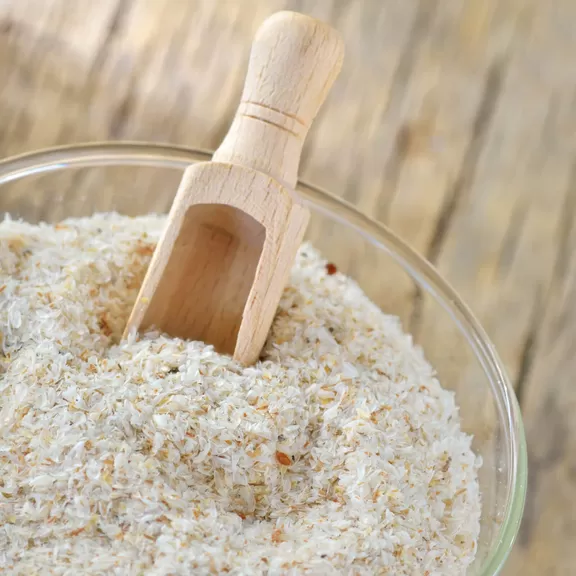 Psyllium seeds in a container with a wooden spoon in it.